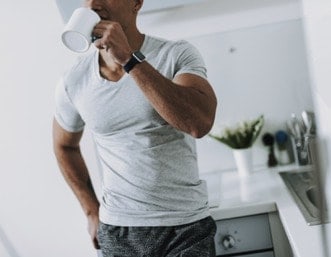 Fit man drinking a cup of coffee to illustrate the performance enhancing benefits of caffiene