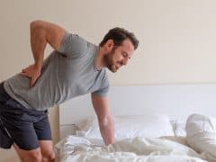 Man waking up in the morning, bent over suffering from sciatica pain