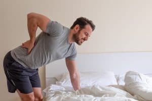 Man waking up in the morning, bent over suffering from sciatica pain
