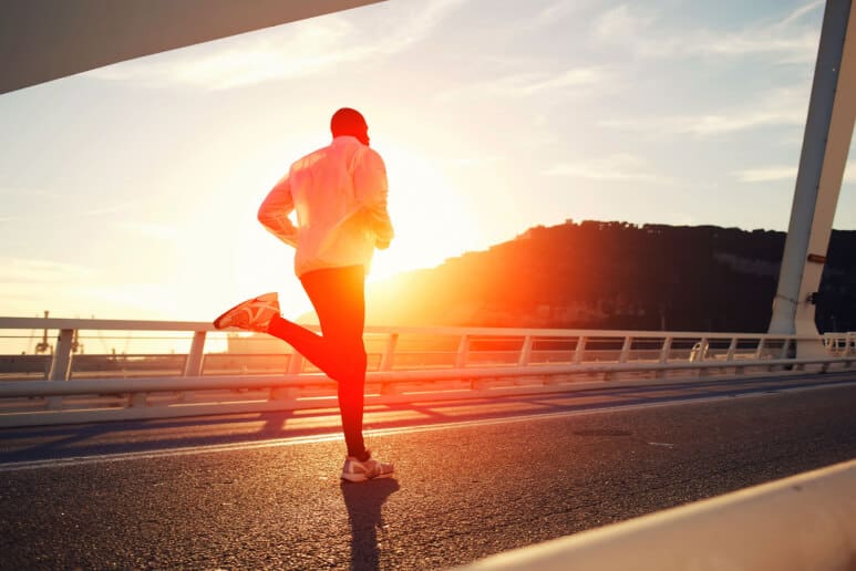 Active man running while sun sets